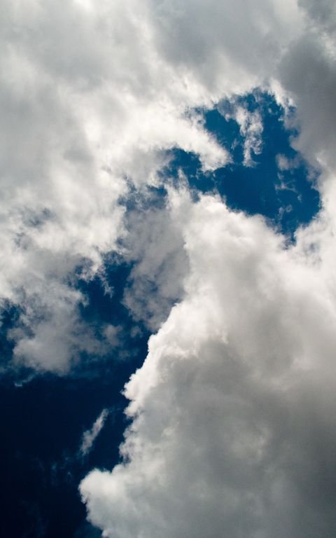 A storm front carving a dark diagonal across deep blue, the original focus on the clouds frame