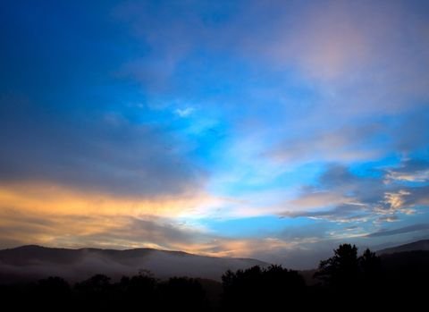 Crepuscular rays fanning over a mountain valley at dusk