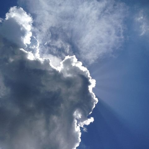 Sun breaking around a dark cloud edge, rays sweeping down the sky