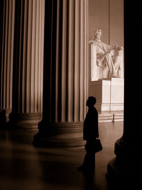 A lone visitor silhouetted before the Lincoln statue