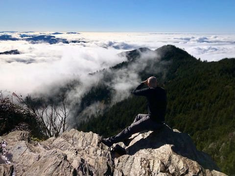 A hiker shading his eyes over the morning cloud sea
