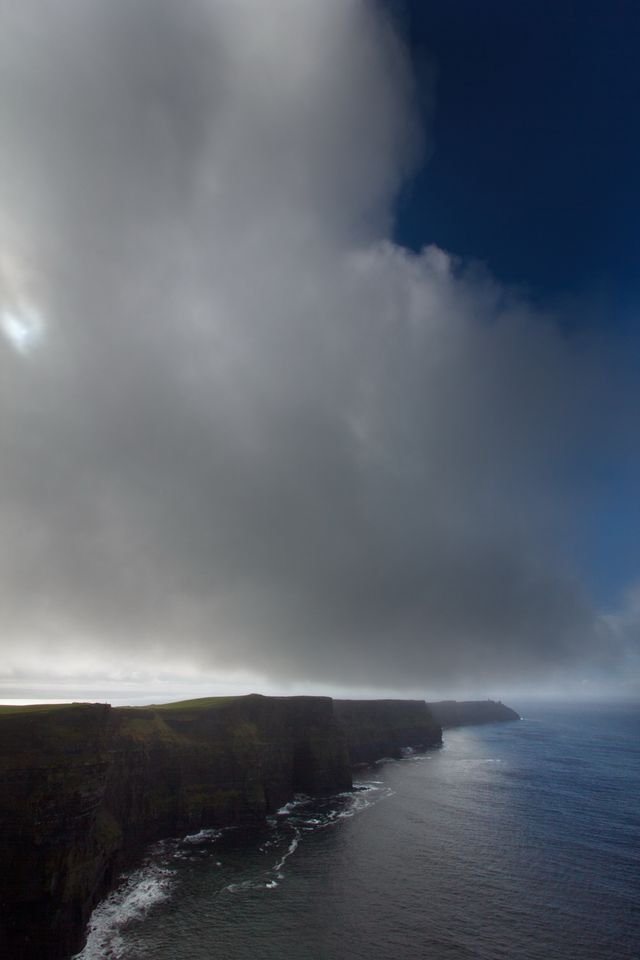 A column of rain drifting over the Cliffs of Moher, the cliff line dark below