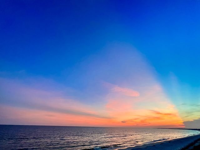 Twilight over the Gulf, a fan of pink cloud above a darkening sea